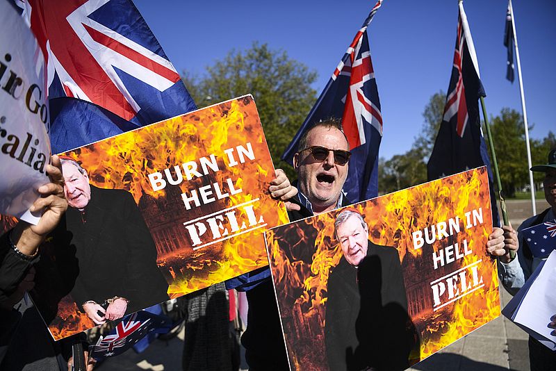 Gegner von Kardinal Pell hält Plakate in den Händen mit der Forderung "Pell burn in Hell".