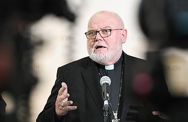 Kardinal Reinhard Marx gestikuliert vor einem Mikrofon