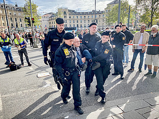 Polizisten tragen Jörg Alt, Sozialwissenschaftler, Sozialethiker und Migrationssoziologe, weg bei einer Straßenblockade für eine andere Klimapolitik am 28. Oktober 2022 in München.