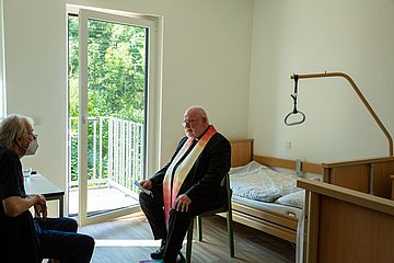 Kardinal Marx (rechts) spricht nach der Segnung mit einem derzeitigen Bewohner der Krankenwohnung.